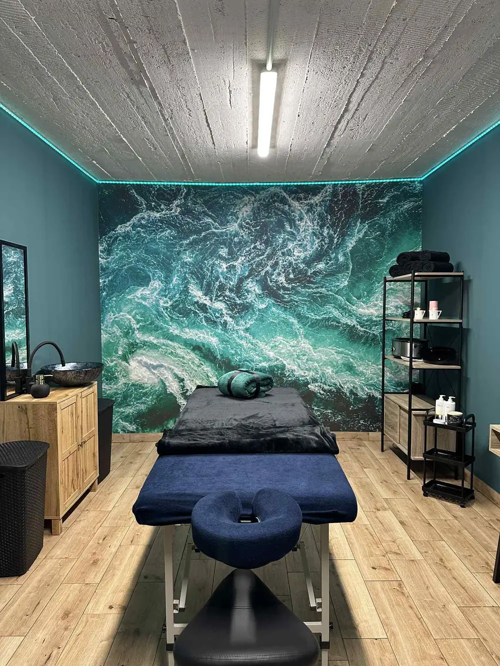 Gabinet DC Massage Studio — stół do masażu na tle fototapety z falami oceanu
